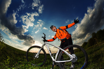 Naklejka premium biker in orange jersey riding on green summer field