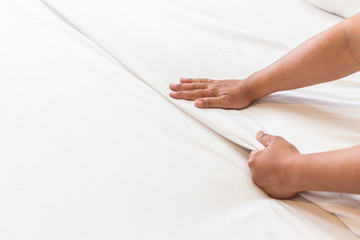Obraz na płótnie Canvas Hand set up white bed sheet in hotel room