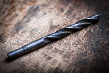 Drill bit on wooden plank