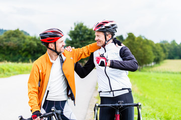 Naklejka premium Bicyclists embrace each other in finish celebrating