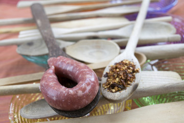 crushed red peppers and pork sausage on two wooden spoon