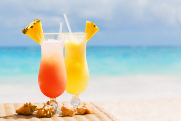 Two tropical fresh juices on white sandy beach
