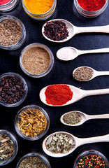 Spices on black background in special jars. Food