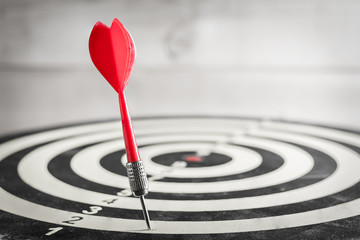 Red dart arrow missed in the target center of dartboard