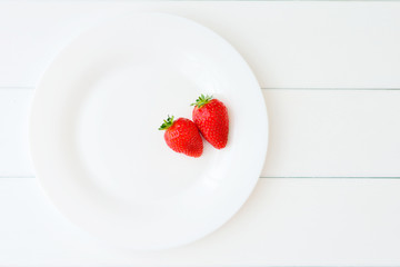 A stack of pancakes with strawberries on a white plate on a wooden white table. Top view 