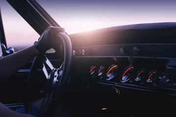 Poster Man holding steering wheel inside car at sunset © Ivan Kurmyshov