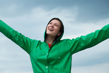 Naklejka premium Woman in raincoat at overcast sky background