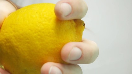 Man hand catching and pulling whole fresh yellow lemon from transparent water with beautiful georgious splash in super slow motion on gray background isolated. Vertical underwater camera Sony rx 10 ii - Powered by Adobe
