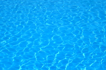 Fototapeta na wymiar Blue and bright water with sun reflection in swimming pool