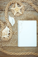 sea shells, notepad and rope on old boards