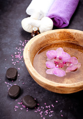 Spa set. Orchid flowers in a bowl with water, zen stones, towels and massage oils