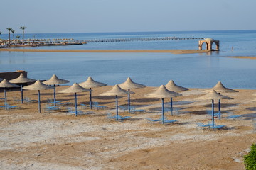 Blue beach chairs and sun umbrellas on sand