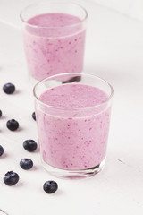 Smoothie from blueberry in glasses on a white wooden background
