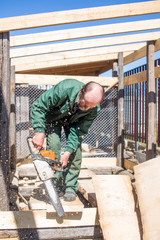 Naklejka na ściany i meble carpenter with a power saw running outdoors. construction of wooden structures. construction of the enclosure for dogs