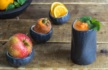 Smoothie made from apple, carrot, orange in black ceramic glass 