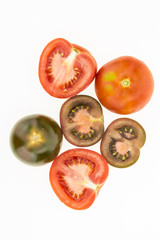 Fresh kumato tomatoes and red tomatoes some cut in half, isolated on white background