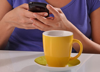 mujer usando telefono celular, enviando mensaje mientras bebe un cafe,