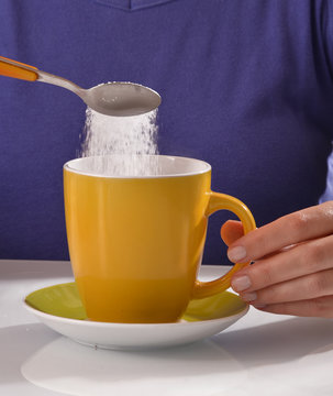 Agregando cucharada de azucar al cafe.