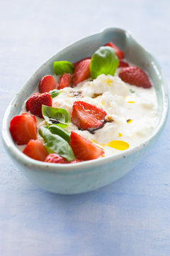 Creamy stracciatella with strawberries, basil, olive oil and balsamic vinegar. Selective focus.