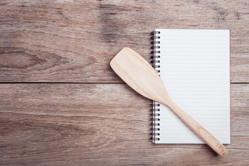 Cooking wooden spatula and lined paper on wooden table top view