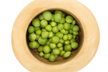 Fresh green peas in wooden bowl closeup, on white background