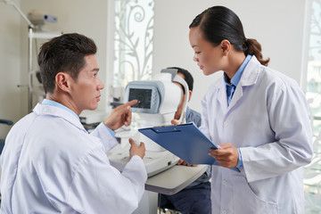 Ophthalmologist giving instructions to nurse when examining patient