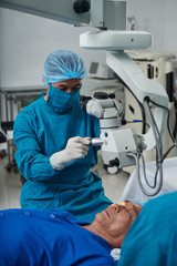 Doctor conducting surgery on eye of senior patient
