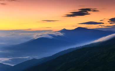 Sunrise landscape of foggy and cloudy mountain valley.