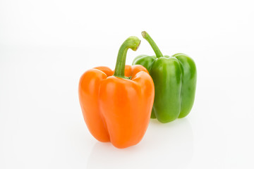Fresh orange and green bell peppers, isolated on white background.
