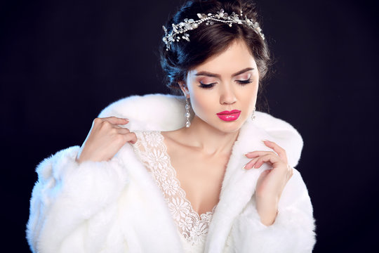 Fashion portrait of beautiful young woman in white fur coat with