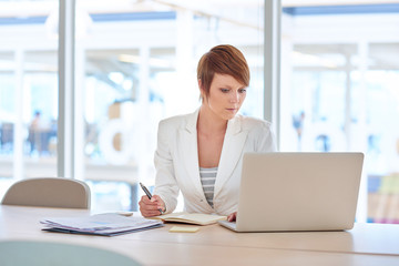 Obraz premium Young businesswoman working with a laptop at her desk