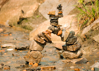 Zen tower bridge of different coloured stones in a shallow stream
