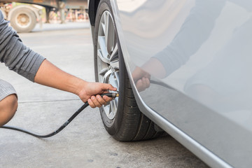 Man checking air pressure and filling air to the tires of his ca