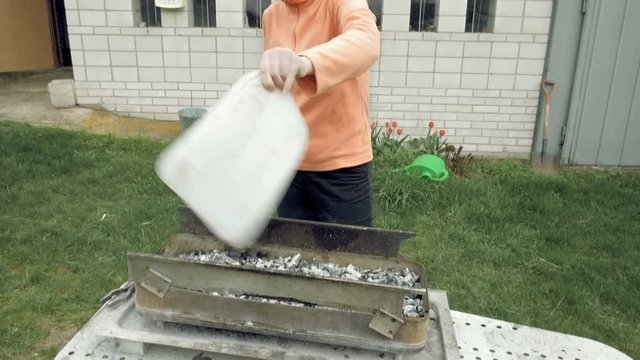 Girl blows coals and fans embers in the barbecue bbq brazier. Outdoors picnic concept. 4K UHD video footage.