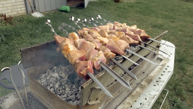 Barbeque skewers with meat cooking on hot coal ember brazier Outdoors picnic concept. 4K UHD video footage.