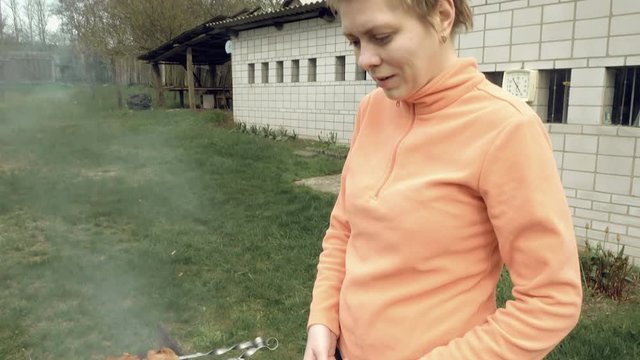 Girl cooks barbeque skewers with meat on hot coal ember brazier Outdoors picnic concept. 4K UHD video footage.