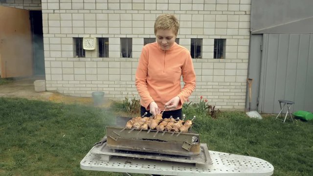 Girl cooks barbeque skewers with meat on hot coal ember brazier Outdoors picnic concept. 4K UHD video footage.