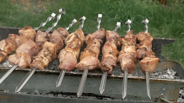Barbeque skewers with meat cooking on hot coal ember brazier Outdoors picnic concept. 4K UHD video footage.