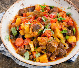 Beef stew with vegetables on a wooden table.
