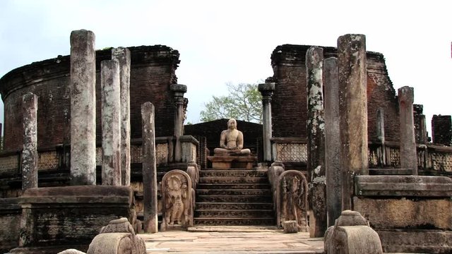 View to the Buddha statue in the ruins of a building in the ancient city of Polonnaruwa, Sri Lanka.