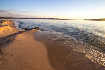 Driftwood On Lake Superior Beach. Lake Superior beach bathed in golden light with copy space in the foreground. Pictured Rocks National Lakeshore. Munising, Michigan.