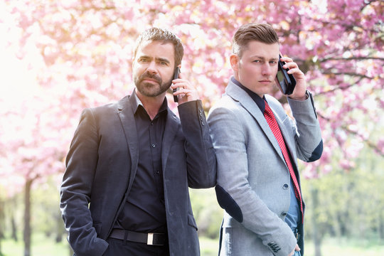 two businessmen outside talking on the phone