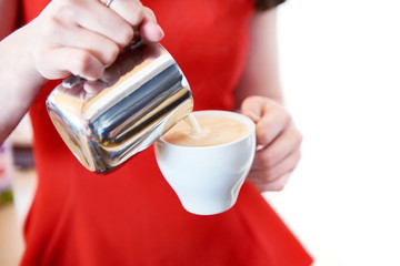 Girl in red is preparing cappuccino in cafe bar