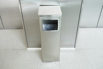 Stainless square bin in front of the elevator.