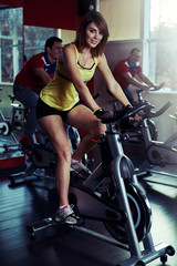 Fototapeta na wymiar Spinning workout in the gym. Group of young people training on bicycles for body and health care. 