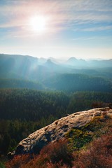 Obraz premium Rocky gulch full of gentle fog and Sun is hidden in heavy mist. Sharp cliffs