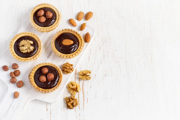 Almond walnut hazelnut chocolate small tarts on a white backgrou