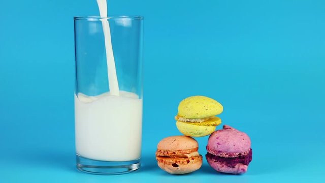 Glass of milk and macaroon on blue background