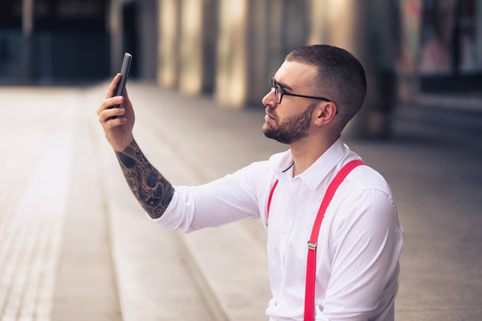 Businessman taking self portrait with iphone. Young hipster man
