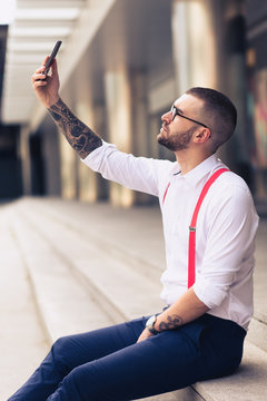 Businessman taking self portrait with iphone. Young hipster man